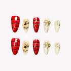 Teddy’s Tartan Waltz: red plaid and cream almond press-on nails with teddy bear and bow decorations, set arranged on a pale background.
