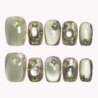 Verdant Relic short rounded-square nails in olive and pale green with gold-colored borders and raised accents.