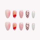 Coquette’s Cherry Pearl: pink and white almond press-on nails with red cherry accents, black dots and raised swirls, set arranged on a pale background.