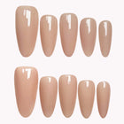 Nude Moonbeam glossy nude almond press-on nails arranged in two rows on white.