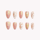 Nereid's Rosy Pearl: pink and white almond press-on nails with gold-tone swirls and shell-like lines, set arranged on a pale background.