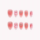 Ariadne’s Rosy Thread: pink almond press-on nails with raised swirls and sparkling accents, set arranged on a pale background.