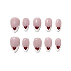 Wonderland's Ruby Heart nude pink almond nails with white French tips and small red hearts, arranged on white.