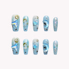 Cetus Starlight Voyage: long blue coffin press-on nails with moon and star shapes, glitter and raised swirls, set arranged on a pale background.
