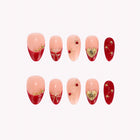 Star-Crossed Ruby: red and nude almond press-on nails with gold-toned hearts, tips and tiny stars, arranged on a pale background.