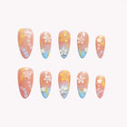 Waikiki Floral Drift: pink almond press-on nails with pastel blue and yellow tips and small flowers, set arranged on a pale background.