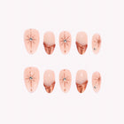 Cassiopeia’s Bronze: nude almond press-on nails with copper-toned French tips and starburst details, arranged on a pale background.