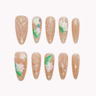 Undine's Lotus Whisper long nude almond nails with green leaves, white flowers and fine raised translucent lines.