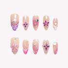 Amphitrite’s Violet Reef: pink and purple almond press-on nails with raised flowers, shell-like ridges and sparkling accents, set arranged on a pale background.