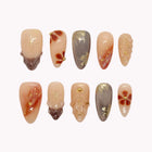 Sienna Gold Sonnet almond nails in nude, amber and olive with brown flowers, gold-colored lines and textured accents.