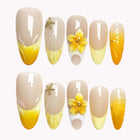 Starfish Sunbursts: nude and yellow almond press-on nails with a raised yellow flower, starfish and curved tip details, set arranged on a pale background.