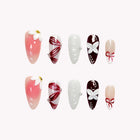 Coppélia’s Ruby Ribbon: pink, white and burgundy almond press-on nails with bows and ribbon-like stripes, set arranged on a pale background.