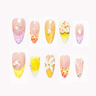Limoncello Glass Garden: yellow, pink and lavender almond press-on nails with flowers, citrus-slice motifs and dotted tips, set arranged on a pale background.
