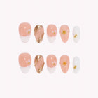 Aphrodite’s Golden Petal: peach and white press-on nails with gold-toned curves and small raised flowers, arranged on a pale background.