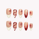 Scarlet Supernova: nude almond press-on nails with white and red tips, red swirls and starbursts, set arranged on a pale background.