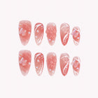 Blush Butterfly Waltz: pink almond press-on nails with white swirls and raised translucent butterfly accents, arranged on a pale background.