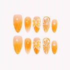 Tangerine Dreamscape: orange-yellow almond press-on nails with citrus slices and raised flowers, arranged on a pale background.