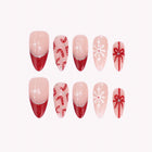 Clara’s Peppermint Waltz: pink almond press-on nails with red French tips, candy canes, bows and white snowflakes, set arranged on a pale background.