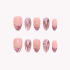Lyra’s Mauve Stardust: pink and mauve almond press-on nails with metallic swirls and gold-toned stars, arranged on a pale background.