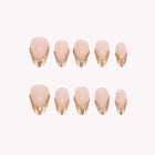 Aurelia’s Molten Edge: nude almond press-on nails with sculpted gold-toned French tips, arranged on a pale background.