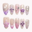 Amethyst Star Shimmer pink and nude almond nails with purple flowers, translucent swirls and tiny silver-colored accents.