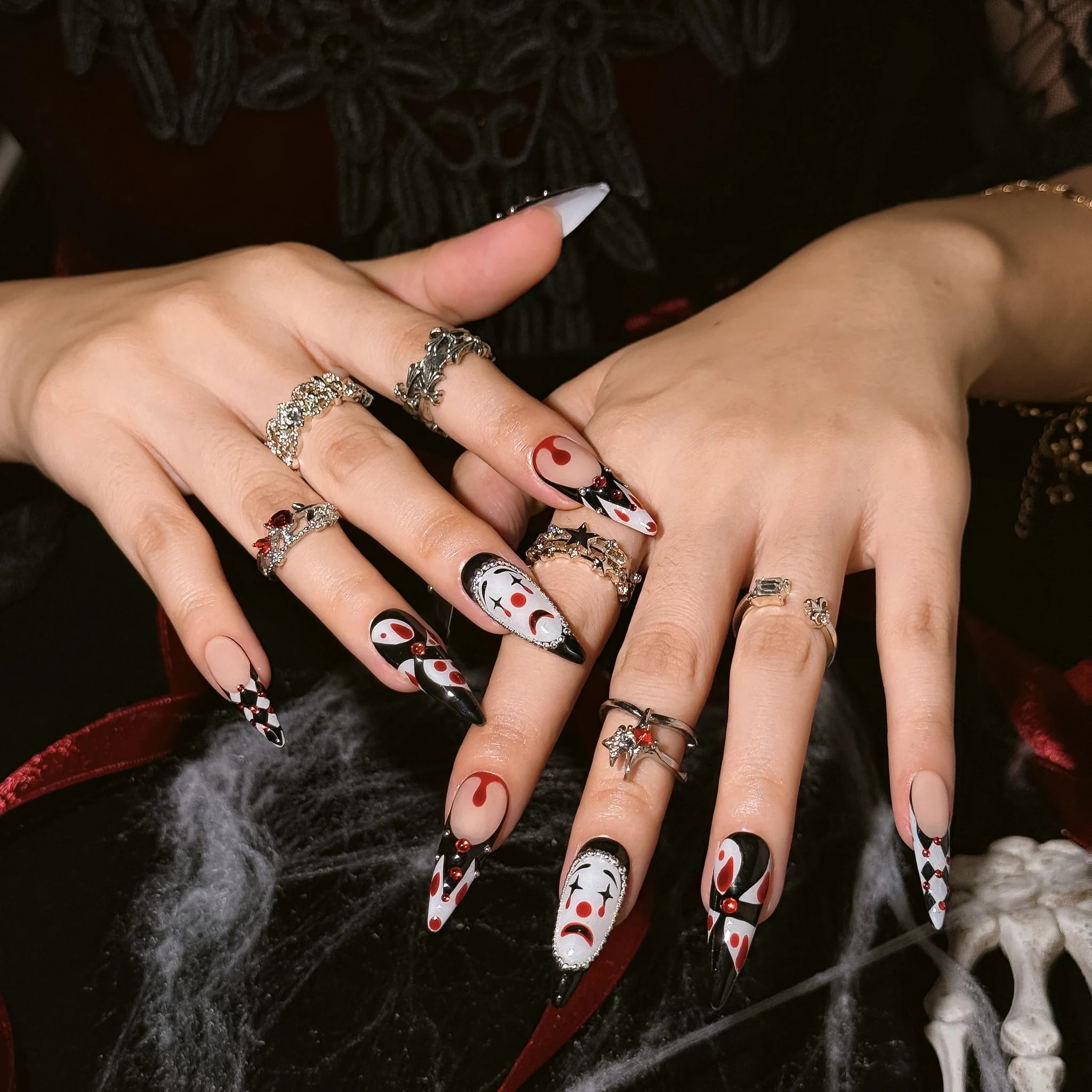 Crimson Harlequin Jewel press-on nails worn on both hands in a styled lifestyle setting
