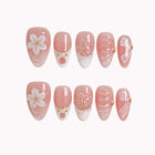 Galatea’s Ivory Bloom short almond press-on nails with pink French tips, raised flowers, and pearl details on white.