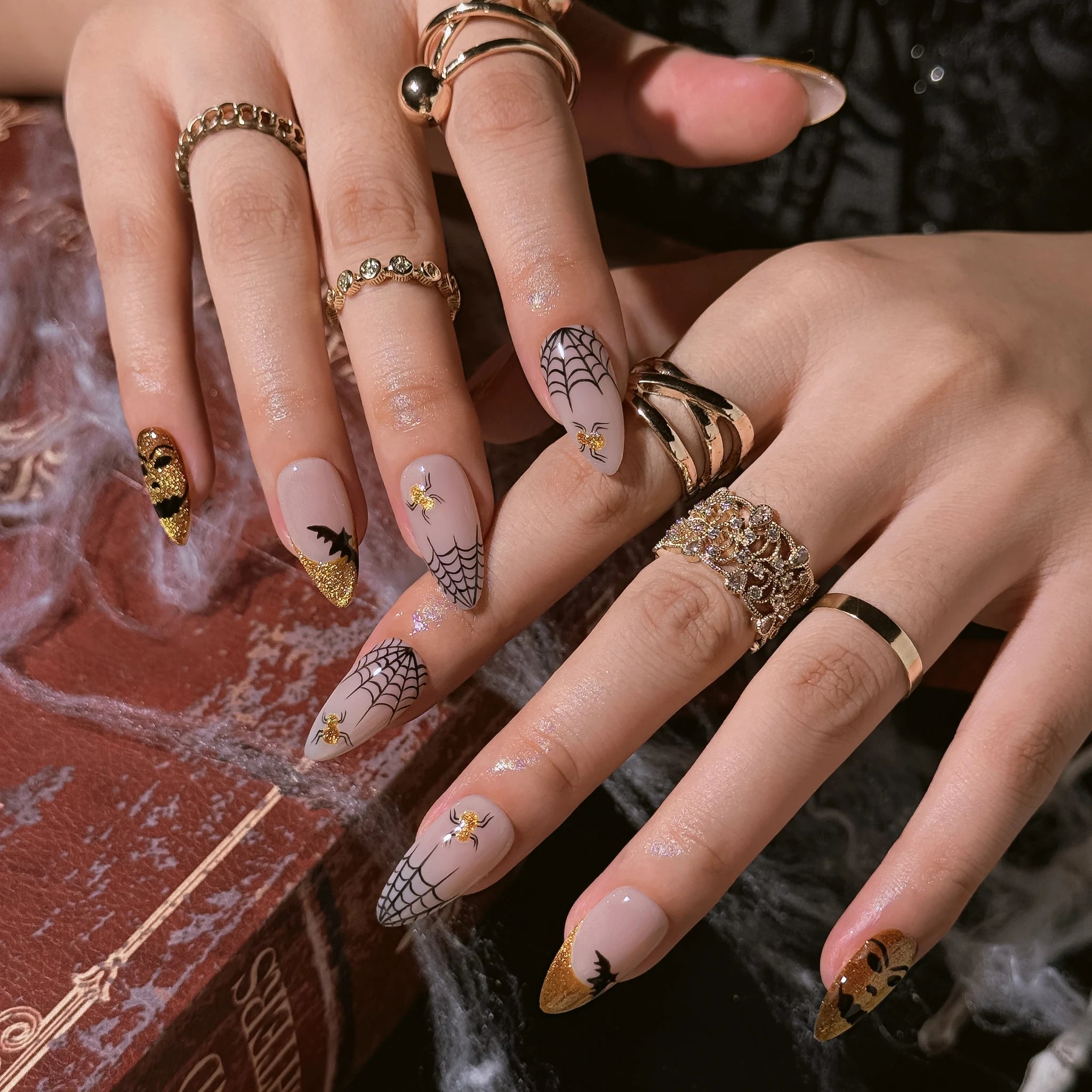 Gilded Web Masquerade press-on nails worn on both hands in a styled lifestyle setting