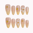 Nereid's Radiance long almond press-on nails with yellow ombré tips, seashells, flowers, and gold details on white.