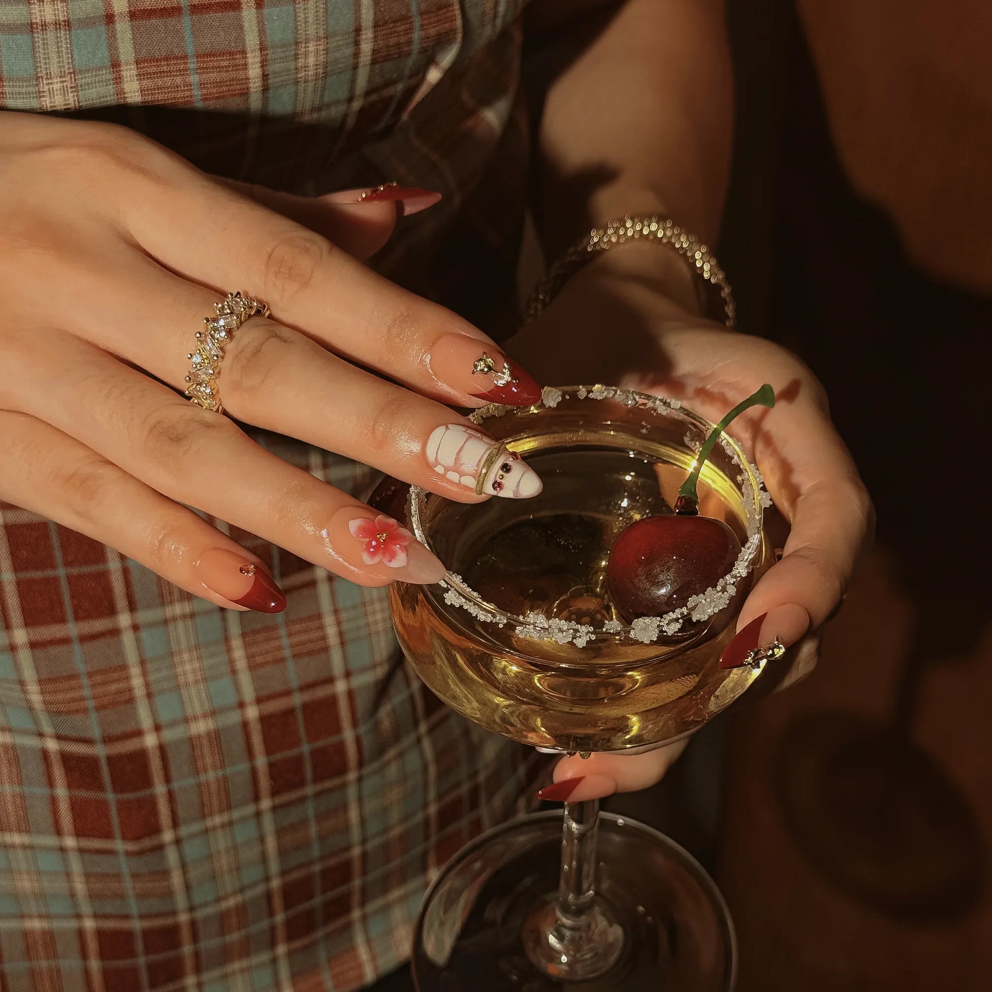 Crimson Garden Jewel: hands around an amber goblet with cherries, showing burgundy French tips and raised pink flower nails