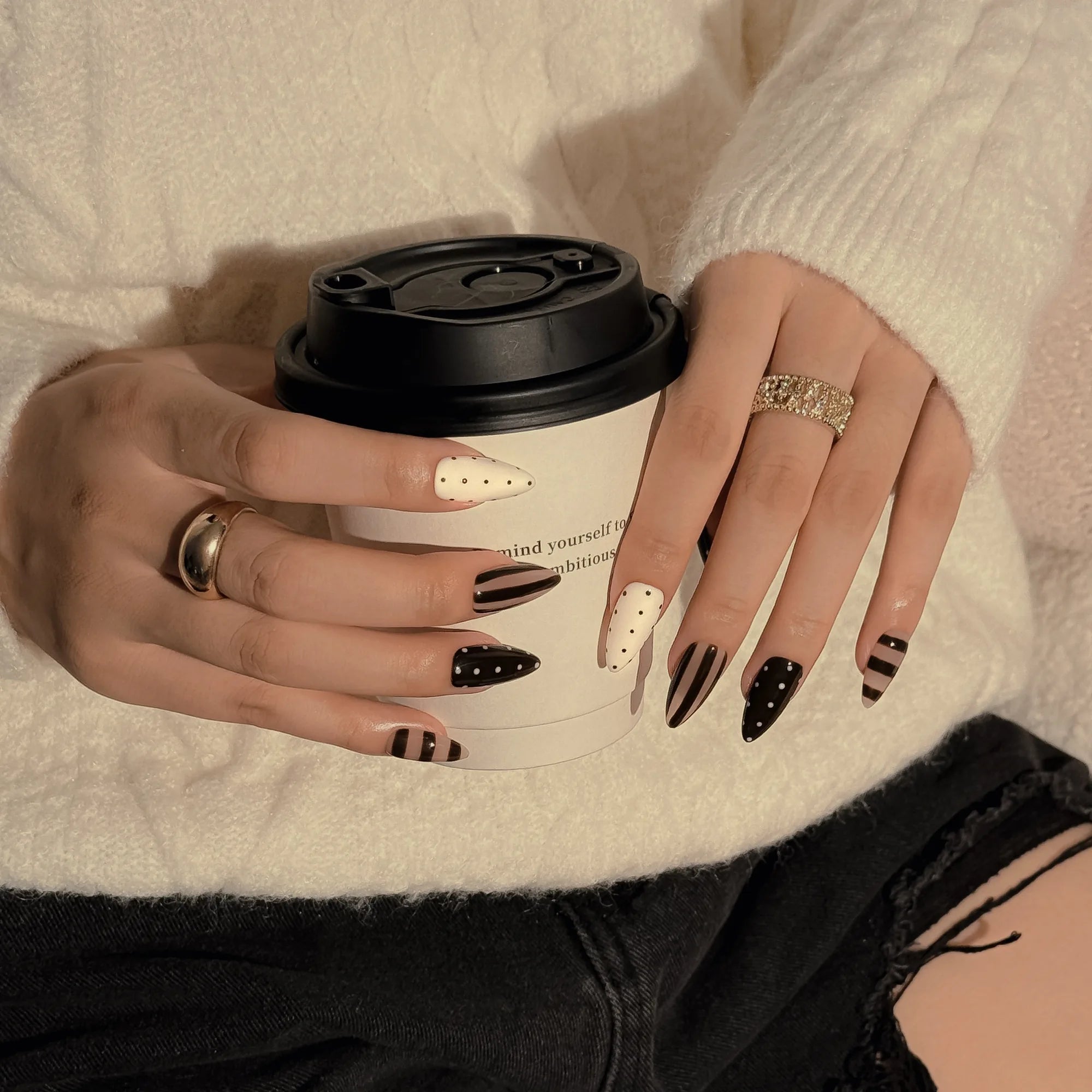 Cocoa Dot Rhythm: hands holding a takeaway cup, wearing brown and white nails with polka dots and stripes