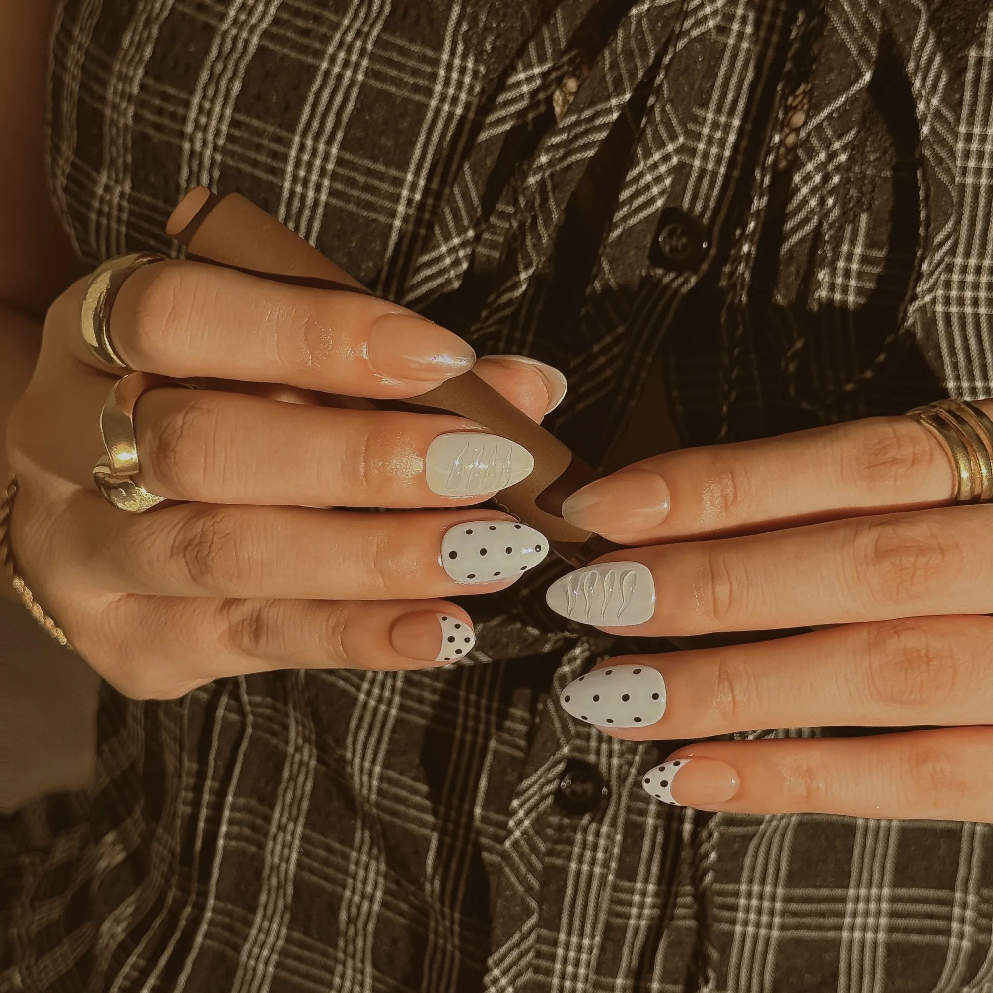 Porcelain Dot Muse: hands against plaid fabric showing white dotted nails, textured white panels and glossy nude accents