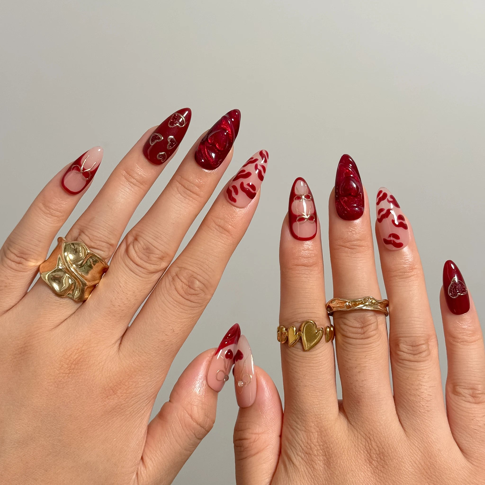Aphrodite’s Stolen Kiss nail set shown across both hands with glossy red and pink designs.