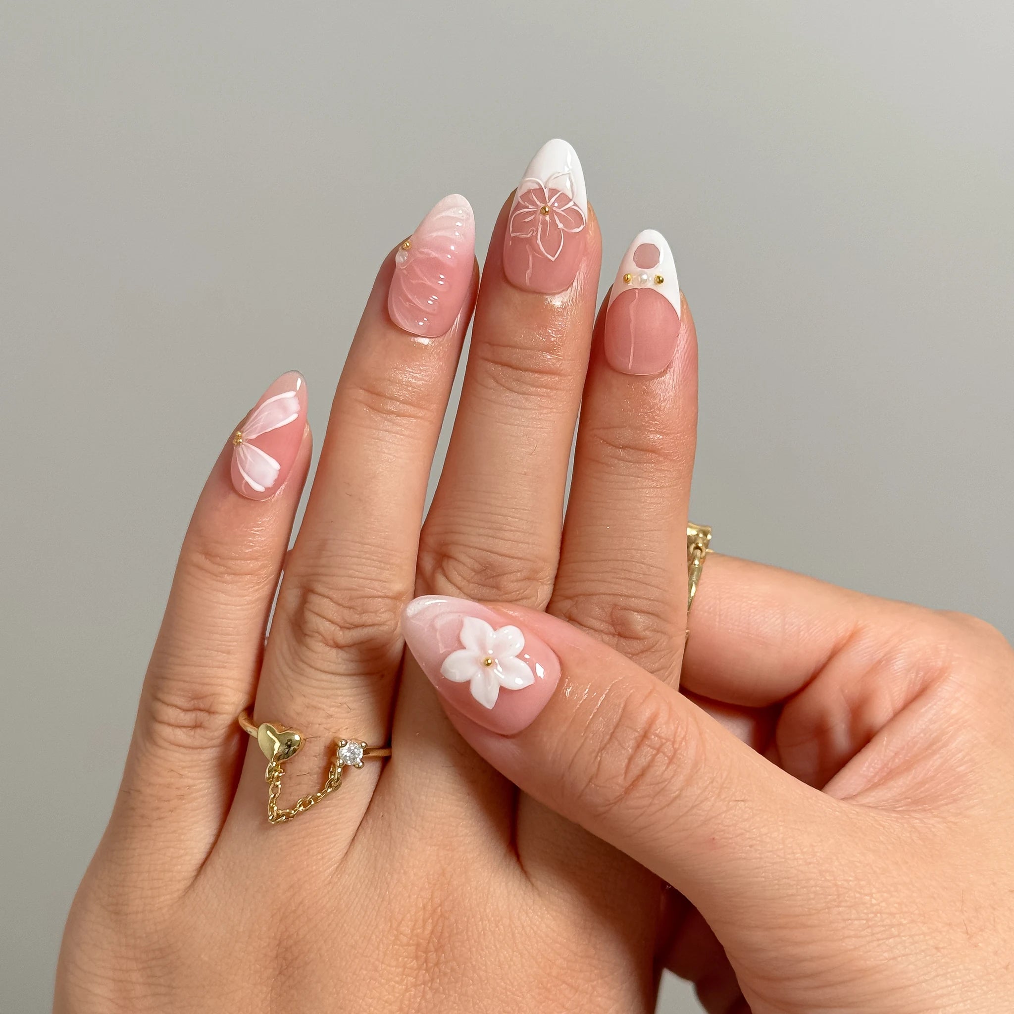 Galatea’s Ivory Bloom short almond press-on nails shown on one hand with a raised floral accent nail.
