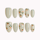 Pomona’s Azure Grove: cream press-on nails with pale blue stripes and tiny orange fruit motifs, arranged on a pale background.