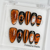 Midnight Pumpkin Portrait press-on nail set arranged in a Veloura Nails display case