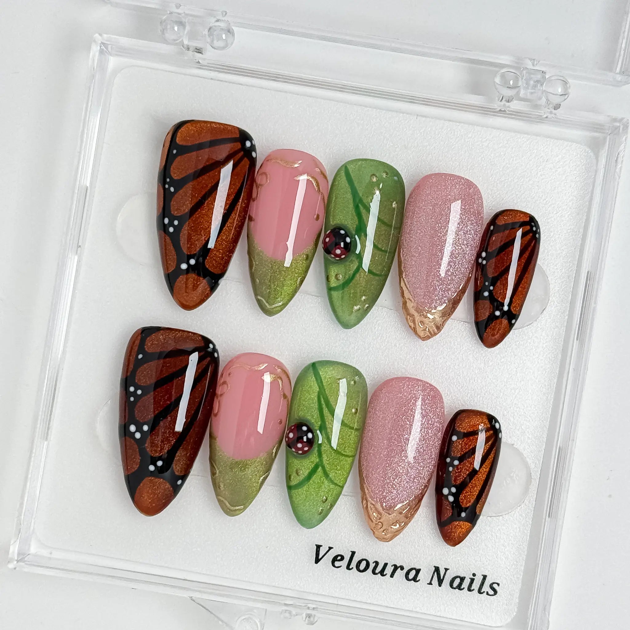 Monarch Meadow Magic press-on nail set arranged in a Veloura Nails display case