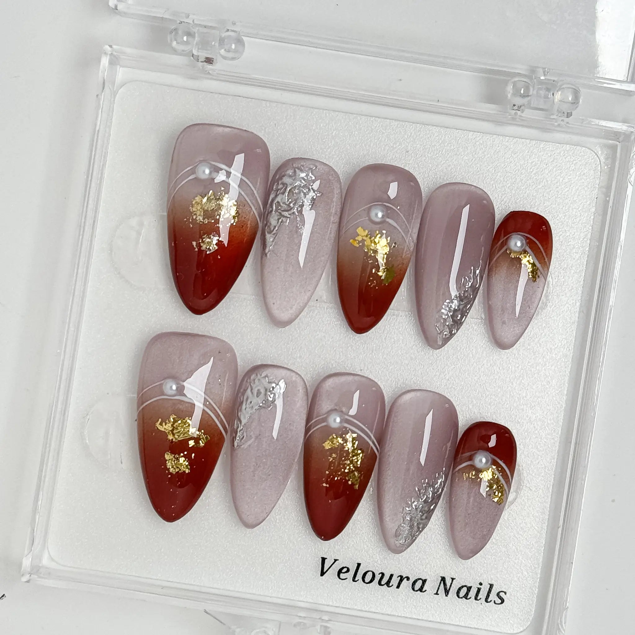 Burgundy Foil Reverie press-on nail set arranged in a Veloura Nails display case