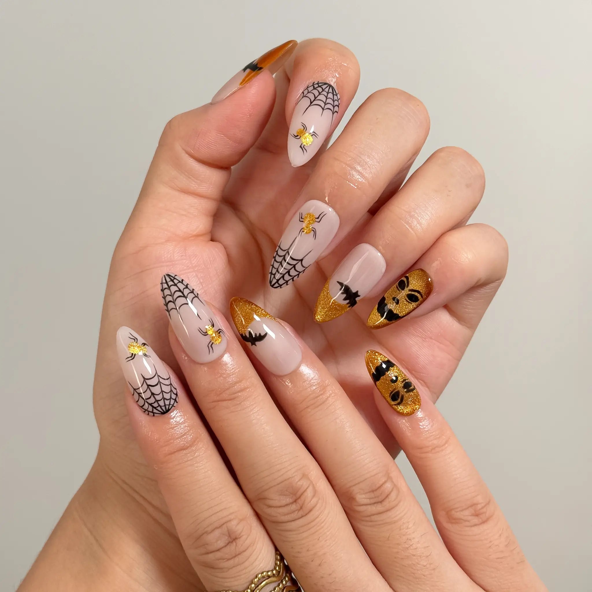 Gilded Web Masquerade long coffin press-on nails with black webs and gold accents shown on hand