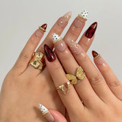 Tortoise Ribbon Reverie long stiletto press-on nails with tortoise shell accents, black polka dots, and gold ribbons shown on hand