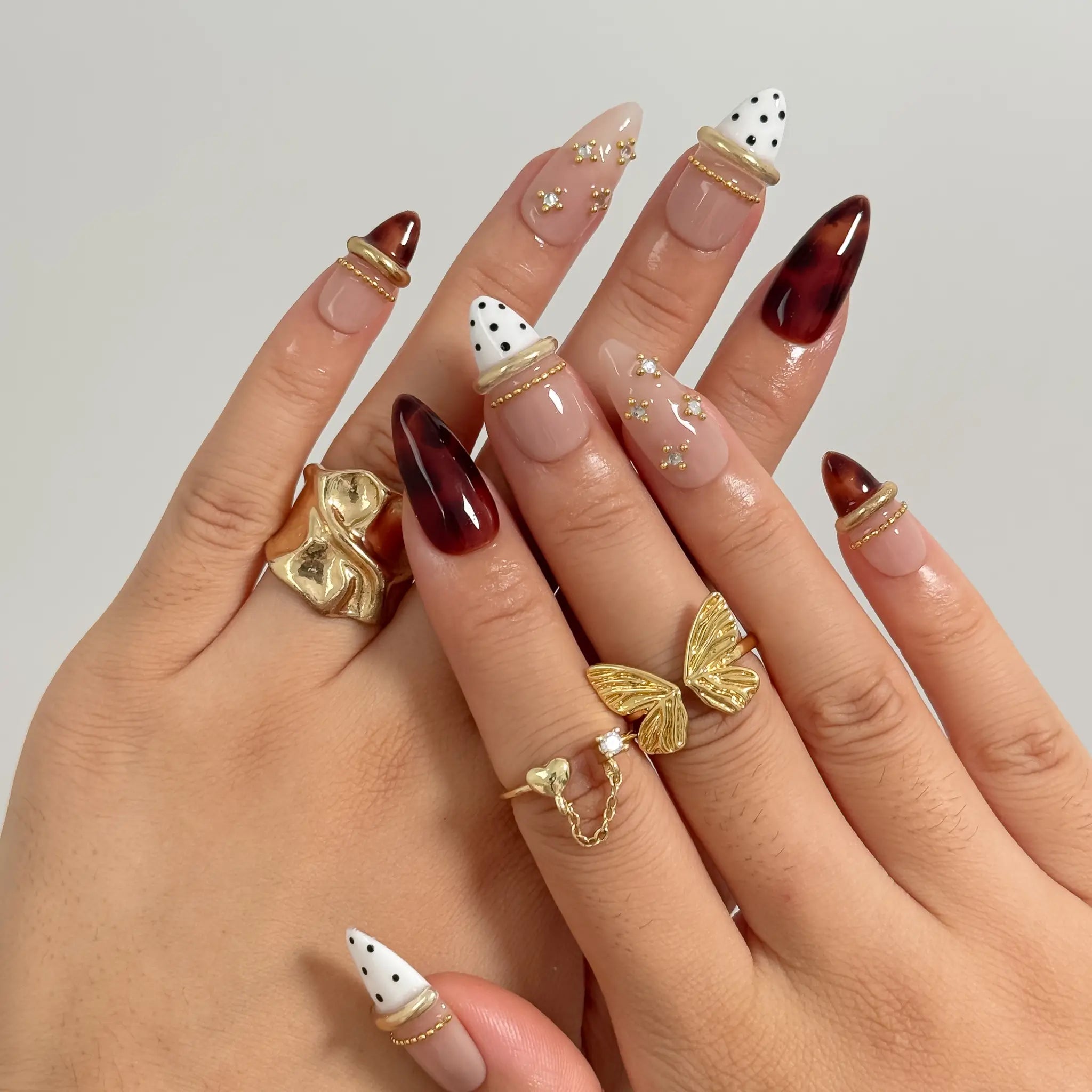 Tortoise Ribbon Reverie long stiletto press-on nails with tortoise shell accents, black polka dots, and gold ribbons shown on hand