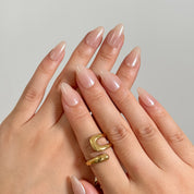 Champagne Silk Aura: glossy nude almond press-on nails with a pearly champagne sheen, shown on raised hands.