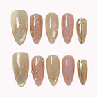 Daphne’s Golden Laurel: nude and gold-toned almond press-on nails with iridescent flakes and raised metallic textures, arranged on a pale background.