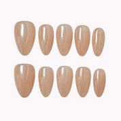 Champagne Silk Aura: glossy nude almond press-on nails with a pearly champagne sheen, arranged on a pale background.