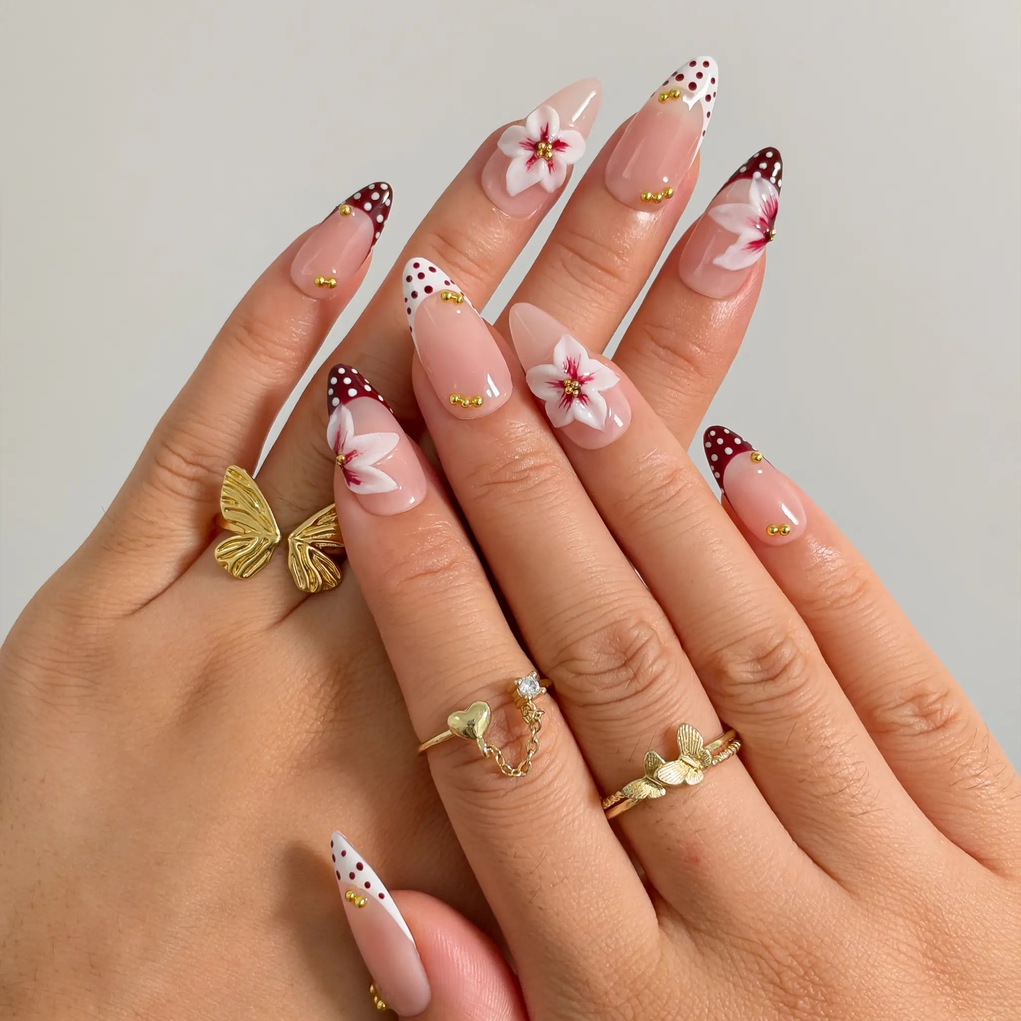 Poinsettia Dot Noel press-on nails shown on hand