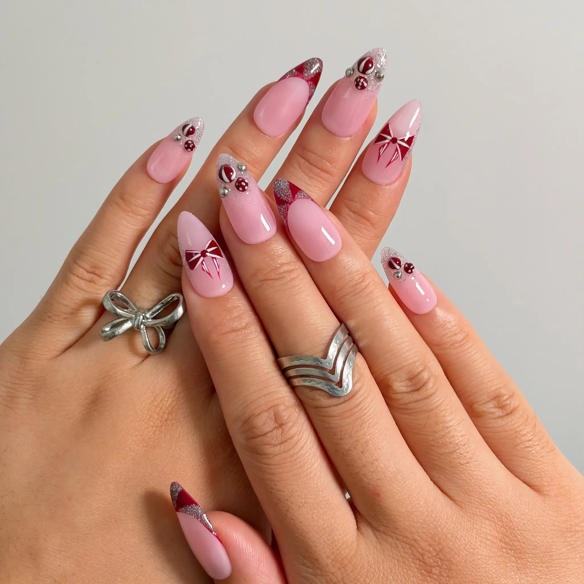Raspberry Ribbon Trinket press-on nails shown on hand