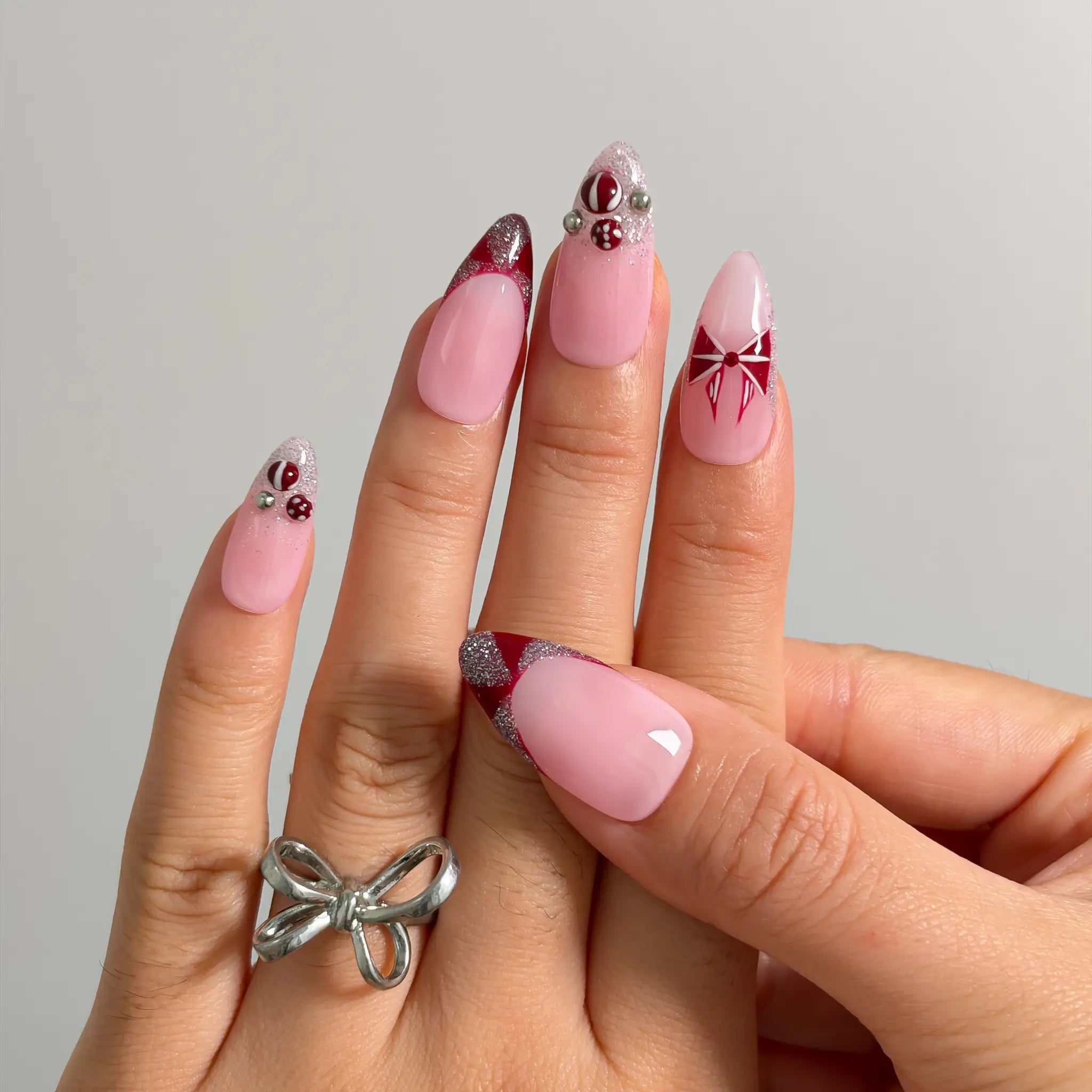 Raspberry Ribbon Trinket Long Almond press-on nails, modeled detail view 2