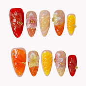 Harvest Citrus Bloom press-on nail set in Red, Orange, Yellow, Nude with red, orange, yellow and nude gradient design with raised flowers on a white background