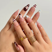 Burgundy Bow Sonata medium almond press-on nails worn on hands, view 1