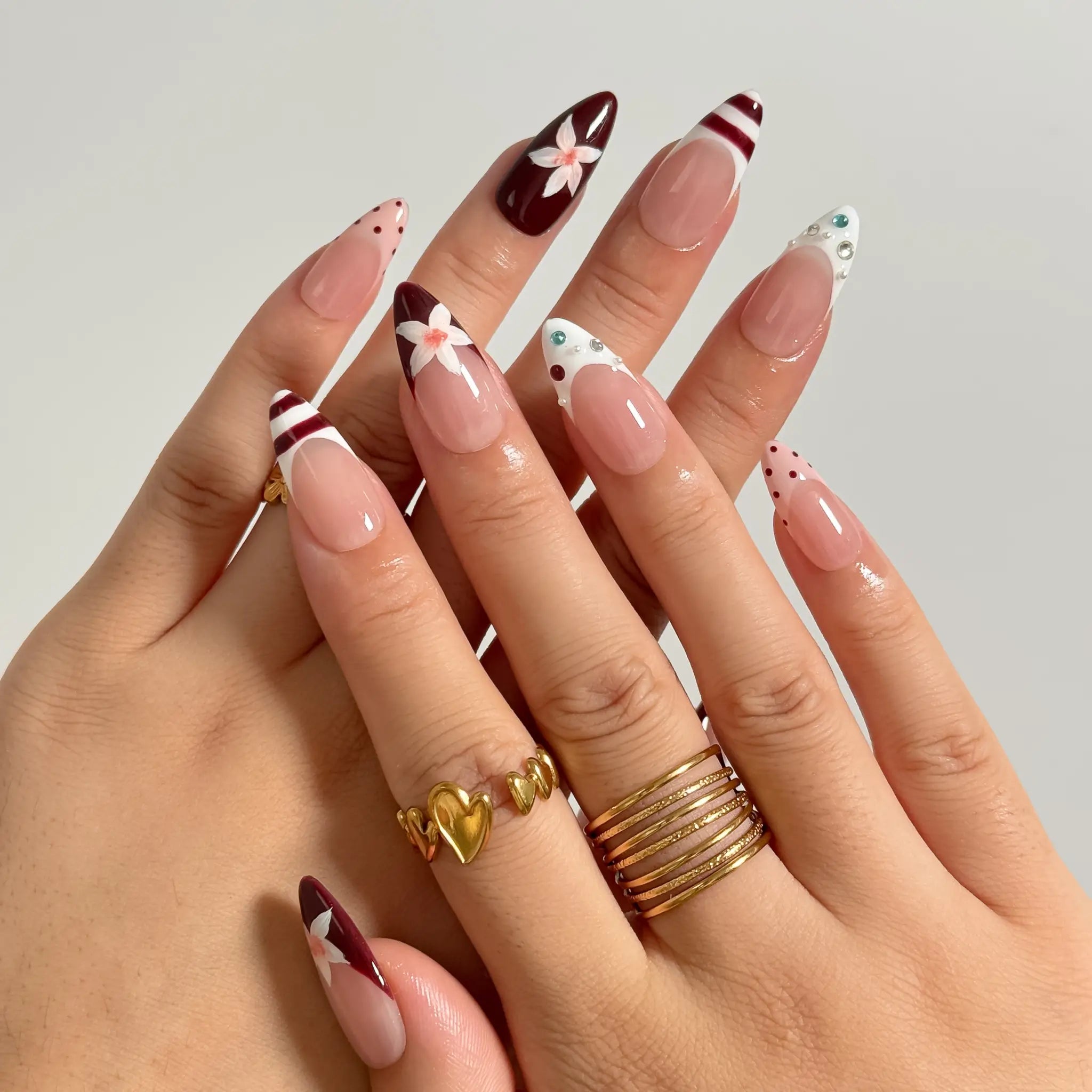 Burgundy Bow Sonata medium almond press-on nails worn on hands, view 1